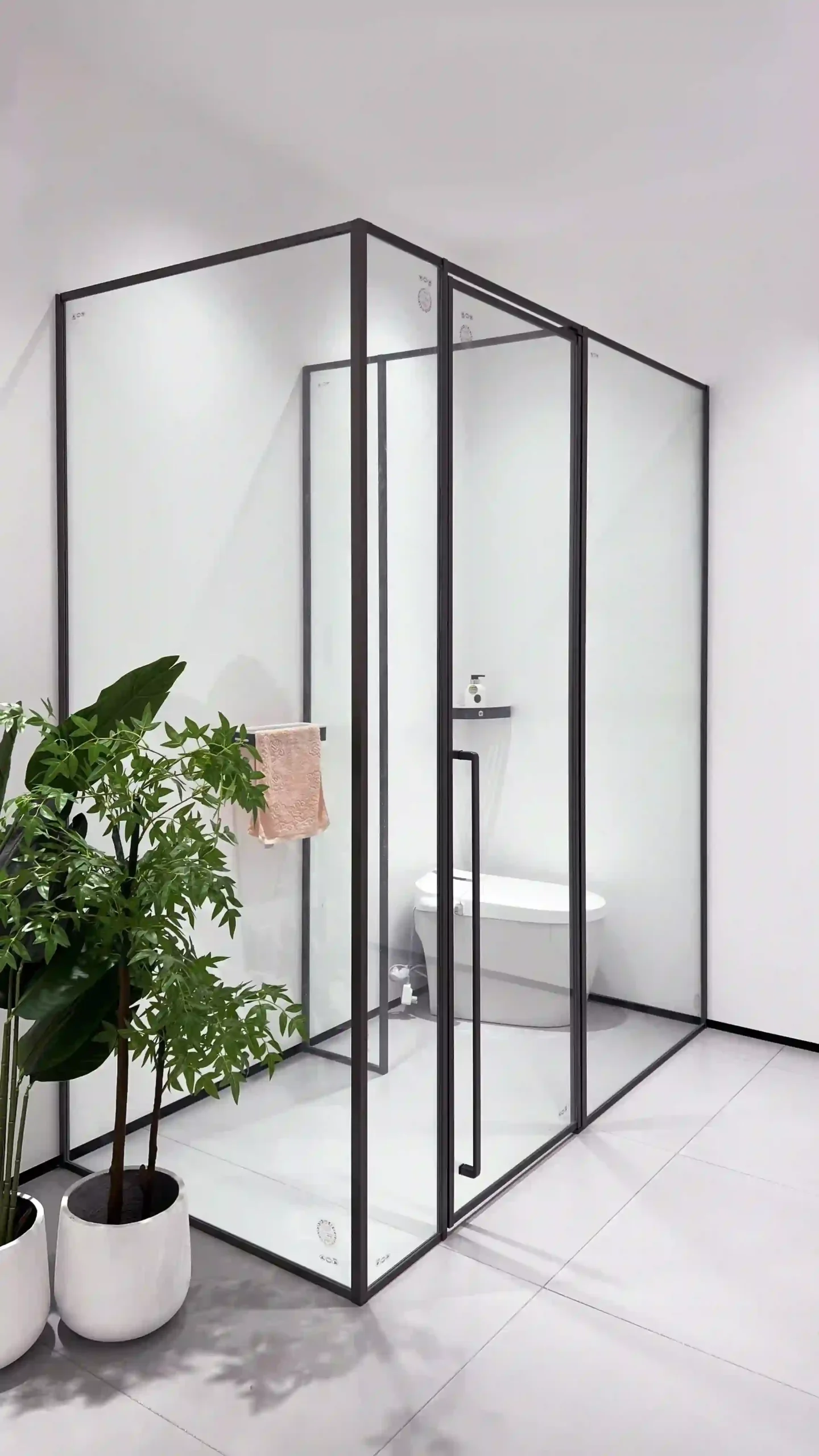 Matte black L-shaped walk-in shower with clear glass and central pivot door, separating wet and dry zones for family-friendly use.