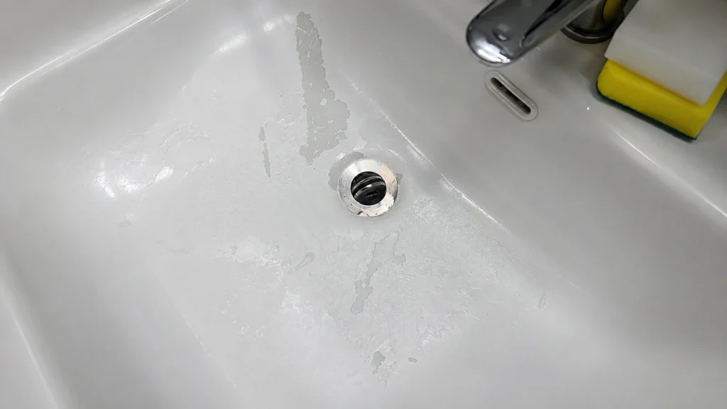 Peeling white paint on a bathroom vanity surface, showing moisture-related finish failure and poor adhesion in a hotel.