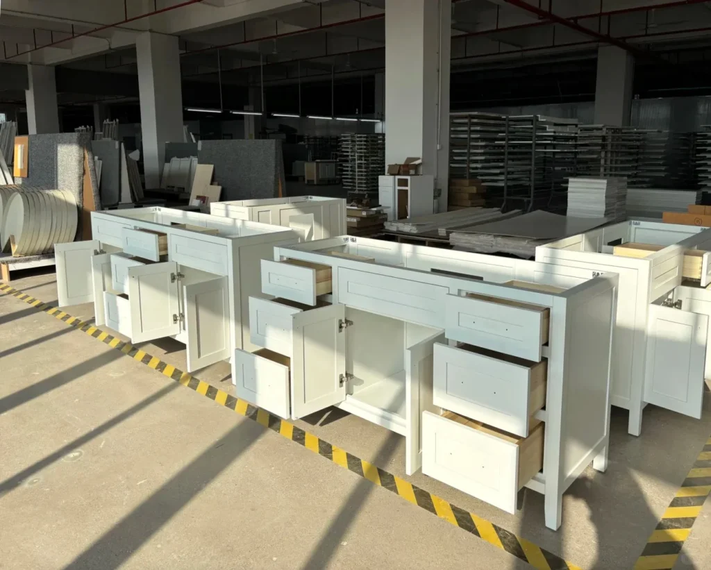 White Shaker bathroom vanity bases on a factory floor for bulk hotel supply, ensuring quality across large quantities.