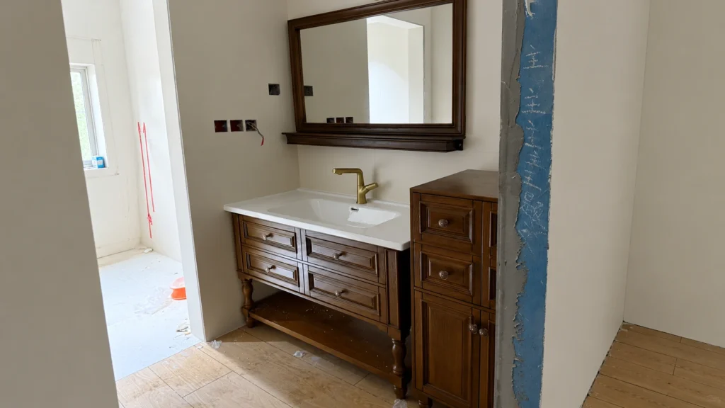 Oak framed vanity with brass faucet on a hotel job site, highlighting a forgiving installation fit for large B2B projects.