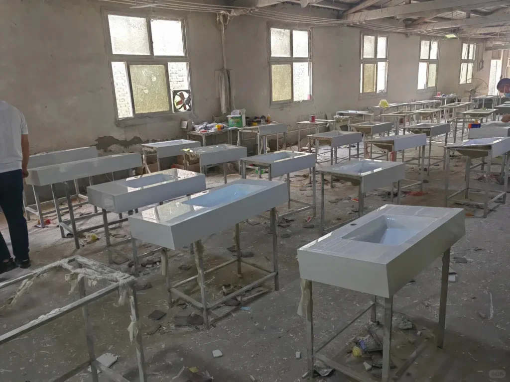 Rows of white vanity tops in a factory, showing mass production consistency for large-scale B2B hotel projects.