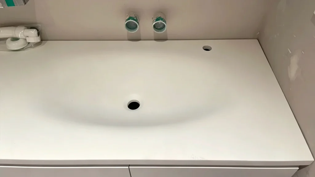 White vanity with misaligned plumbing and faucet holes, illustrating hidden rework costs and site errors for hotel projects.