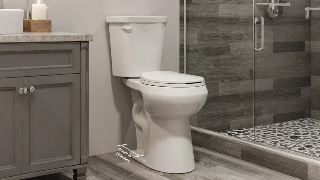 Standard white two-piece toilet displaying a 12-inch rough-in dimension in a modern hotel guest bathroom.