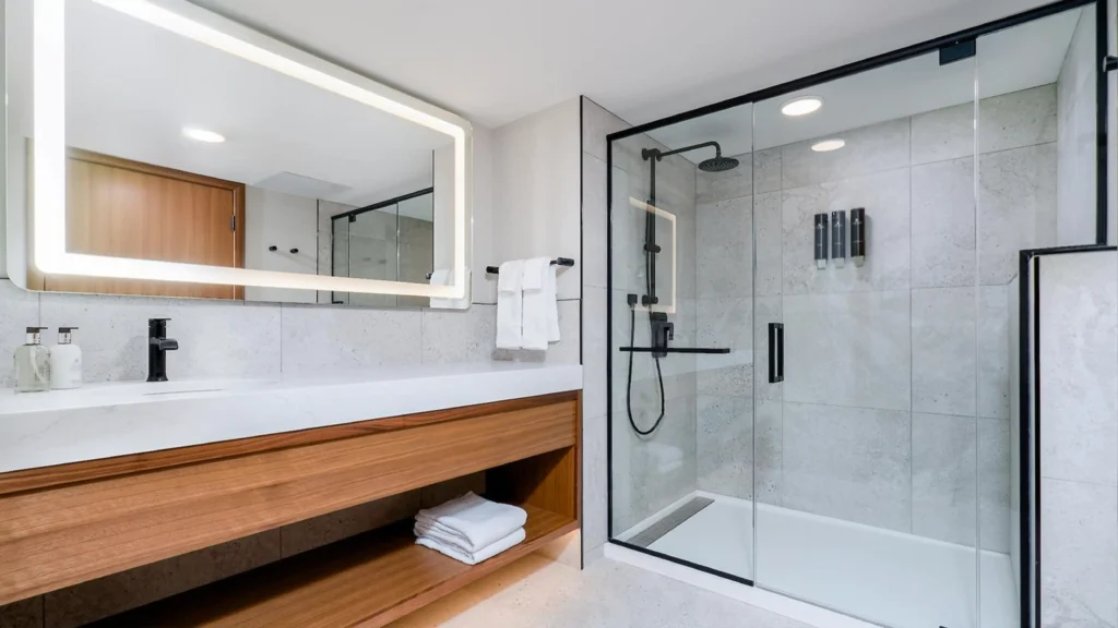 Matte black framed glass shower door enclosure in a modern standard hotel and apartment bathroom.